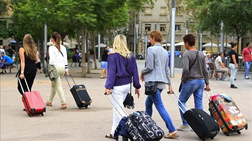 Turistas con maletas de ruedas paseando por una plaza